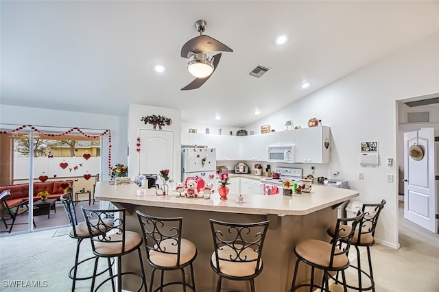 kitchen with lofted ceiling, a breakfast bar area, light colored carpet, white appliances, and white cabinets