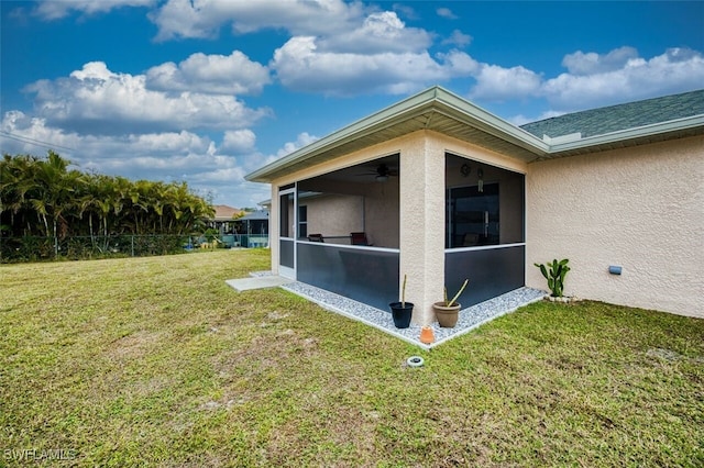 view of home's exterior with a yard, a sunroom, and ceiling fan