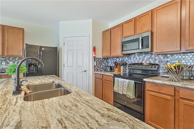 kitchen featuring sink, backsplash, light stone counters, and black appliances