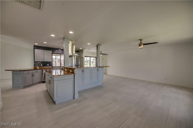 kitchen featuring gray cabinetry, kitchen peninsula, ceiling fan, and a kitchen island