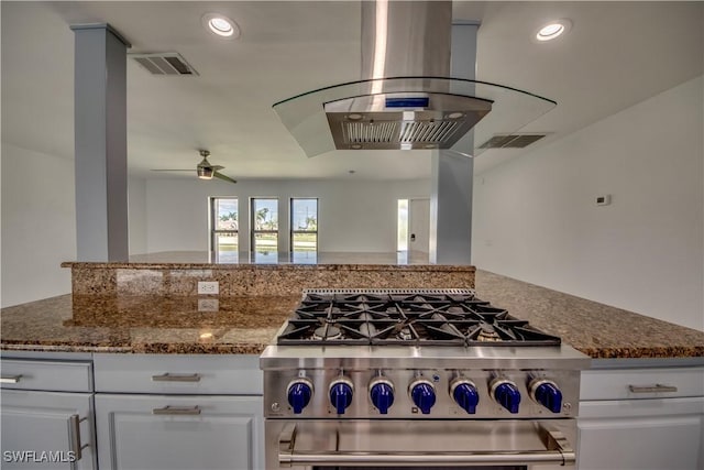 kitchen featuring stainless steel range, island range hood, dark stone countertops, and white cabinets