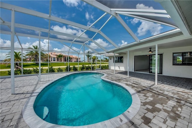 view of swimming pool with ceiling fan, glass enclosure, and a patio area