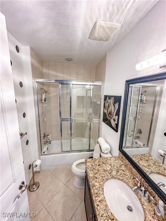 bathroom featuring tile patterned flooring, vanity, toilet, bath / shower combo with glass door, and a textured ceiling