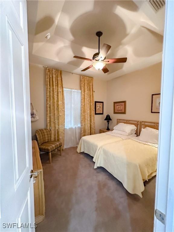 carpeted bedroom featuring visible vents and a ceiling fan
