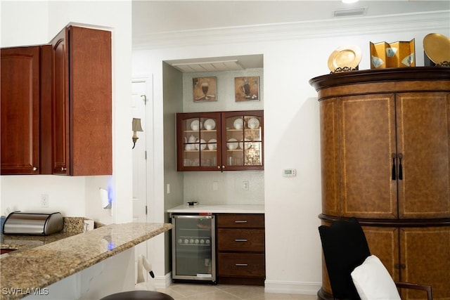 kitchen featuring glass insert cabinets, visible vents, crown molding, light stone countertops, and wine cooler
