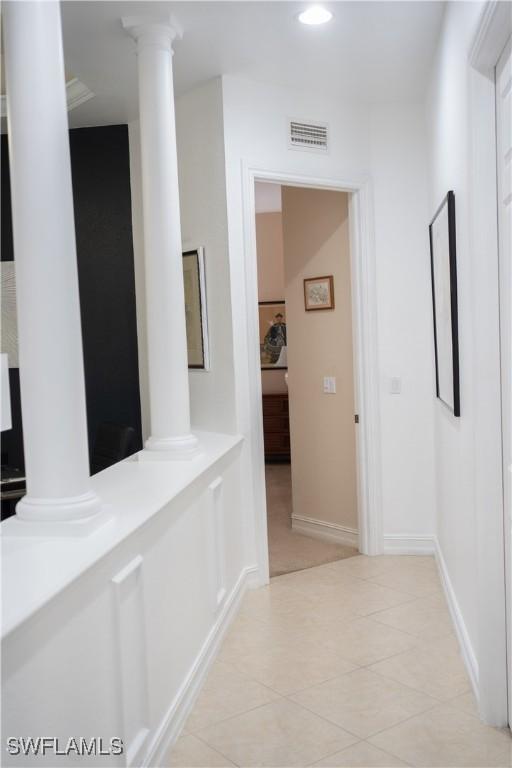 hallway with decorative columns and light tile patterned flooring