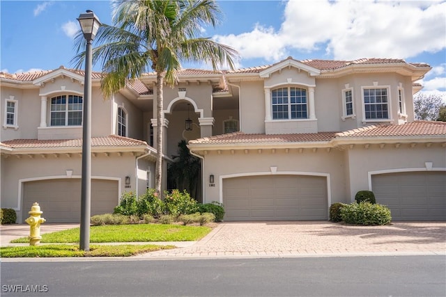 view of front of house featuring an attached garage, stucco siding, a tiled roof, and driveway