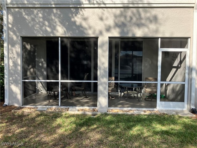 back of property featuring a sunroom and stucco siding
