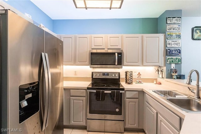 kitchen featuring stainless steel appliances, white cabinetry, sink, and light tile patterned floors