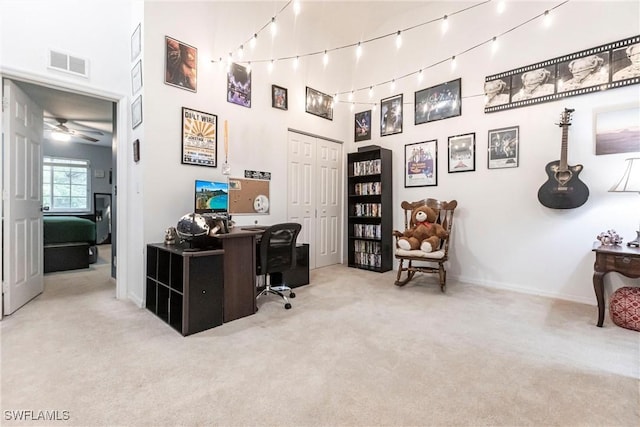 carpeted office featuring a towering ceiling and ceiling fan