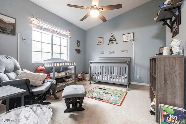 bedroom with ceiling fan, lofted ceiling, carpet flooring, and a crib