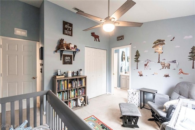 bedroom featuring connected bathroom, light carpet, a closet, a nursery area, and ceiling fan