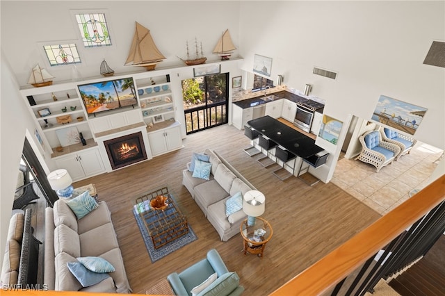 living room featuring a towering ceiling, plenty of natural light, and light hardwood / wood-style flooring