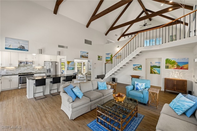 living room featuring lofted ceiling with beams, ceiling fan, and light wood-type flooring