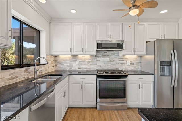 kitchen with sink, stainless steel appliances, tasteful backsplash, white cabinets, and dark stone counters