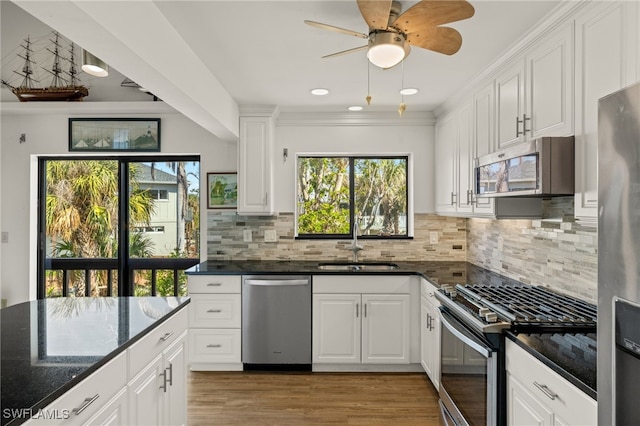 kitchen featuring white cabinetry, sink, stainless steel appliances, and dark stone counters