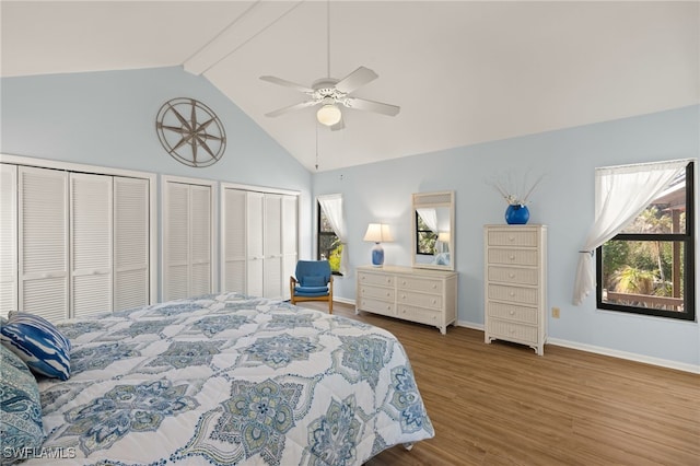 bedroom featuring high vaulted ceiling, two closets, beamed ceiling, ceiling fan, and hardwood / wood-style floors