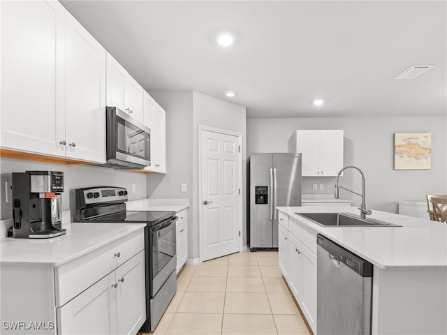 kitchen with sink, light tile patterned floors, an island with sink, stainless steel appliances, and white cabinets