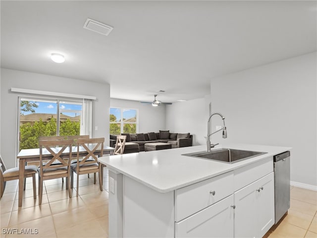 kitchen with dishwasher, an island with sink, sink, white cabinets, and light tile patterned floors