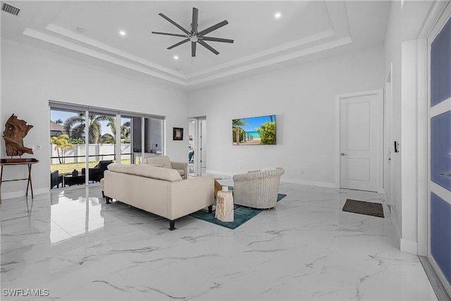 living area with visible vents, a towering ceiling, baseboards, marble finish floor, and a tray ceiling