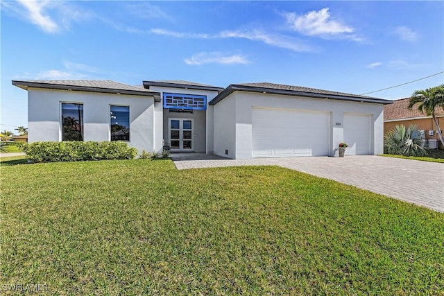 prairie-style home with a garage, decorative driveway, a front yard, and stucco siding