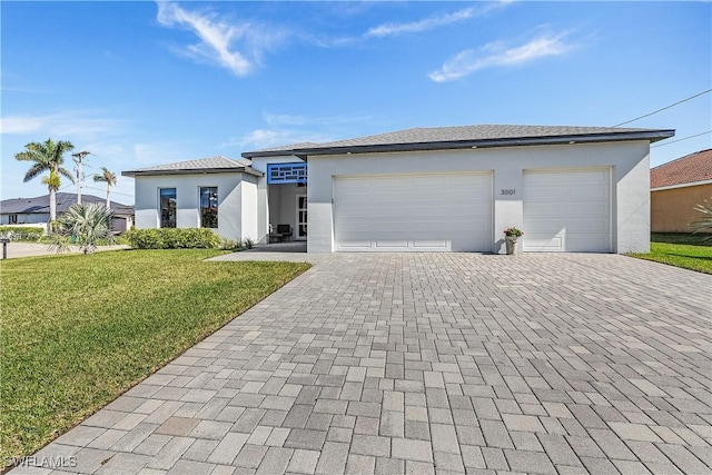 prairie-style house featuring a garage, decorative driveway, a front lawn, and stucco siding