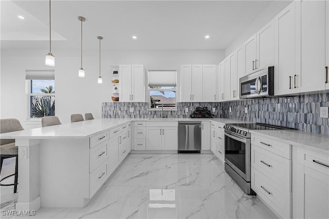 kitchen featuring sink, white cabinetry, a kitchen breakfast bar, stainless steel appliances, and decorative light fixtures