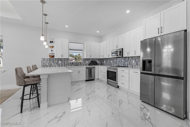 kitchen with marble finish floor, a breakfast bar area, stainless steel appliances, decorative backsplash, and a peninsula