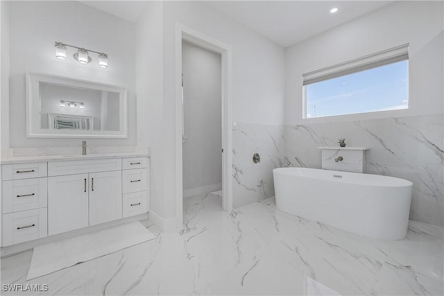 full bath with marble finish floor, a soaking tub, and vanity