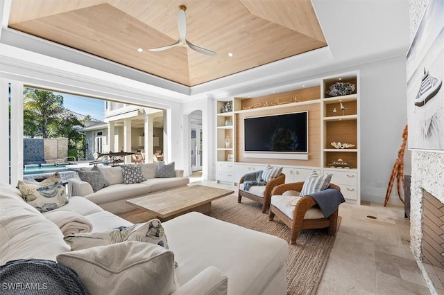 living room with a fireplace, ceiling fan, wood ceiling, a raised ceiling, and built in shelves