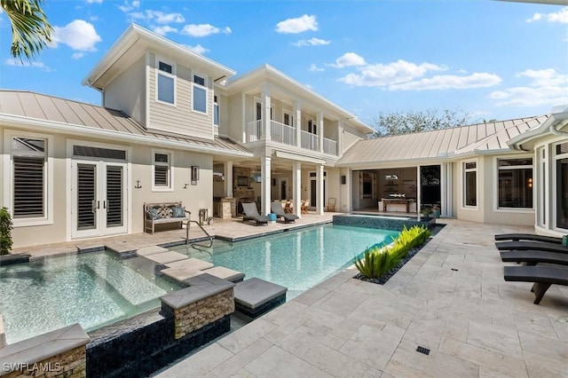 back of property featuring french doors, a swimming pool with hot tub, and a patio area