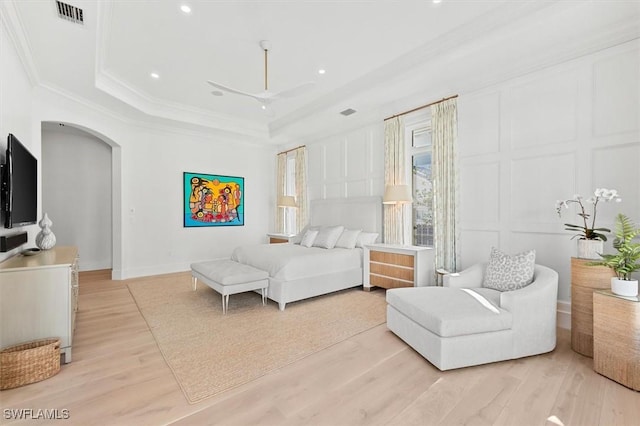 bedroom featuring ornamental molding, light wood-type flooring, and a tray ceiling