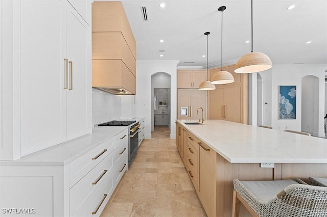 kitchen featuring a large island with sink, high end appliances, sink, and white cabinets