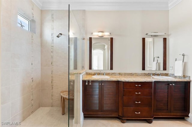 bathroom with tile patterned flooring, crown molding, a tile shower, and vanity