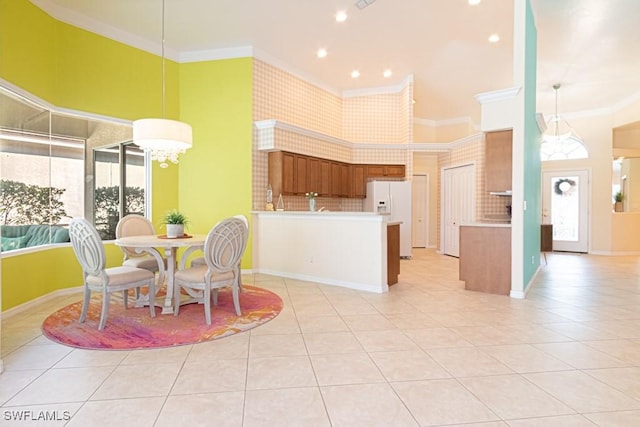 tiled dining area with crown molding, a towering ceiling, and a notable chandelier