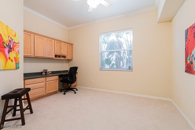 carpeted office featuring crown molding, ceiling fan, and built in desk