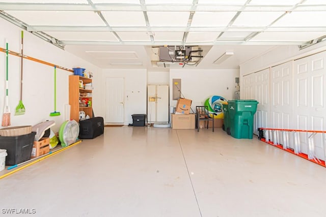 garage featuring a garage door opener and white refrigerator with ice dispenser