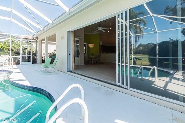 view of swimming pool featuring ceiling fan, a patio, and glass enclosure