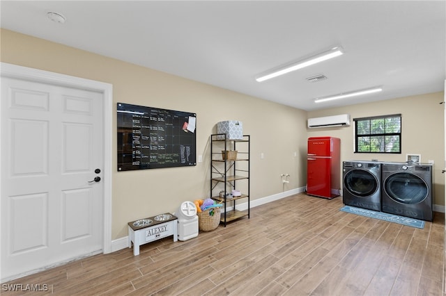 laundry area with a wall unit AC and independent washer and dryer