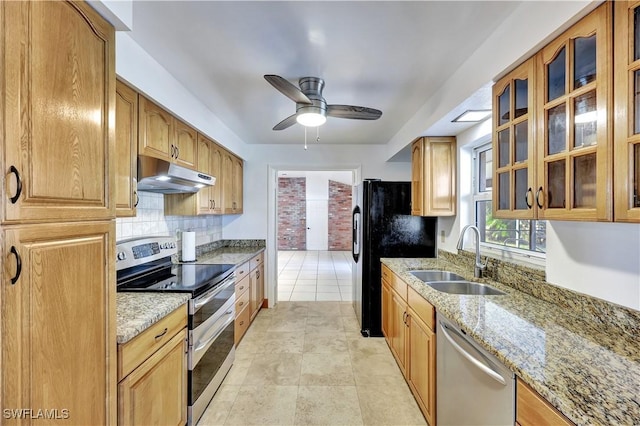 kitchen with sink, ceiling fan, appliances with stainless steel finishes, backsplash, and light stone countertops