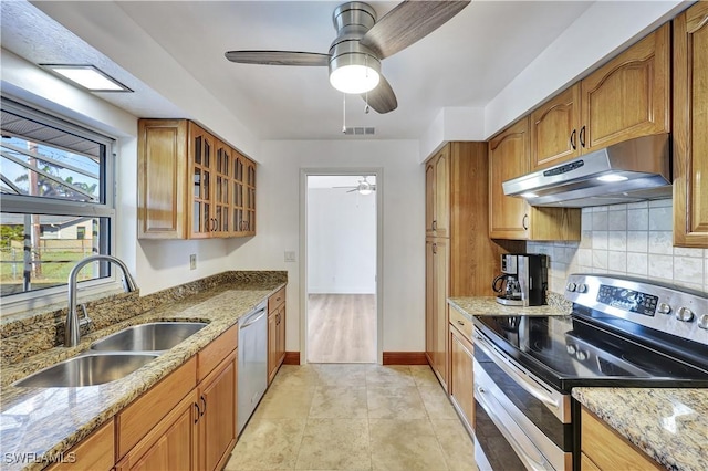 kitchen with light tile patterned flooring, sink, stainless steel appliances, light stone countertops, and decorative backsplash