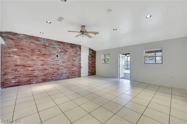 tiled spare room with vaulted ceiling, ceiling fan, and brick wall