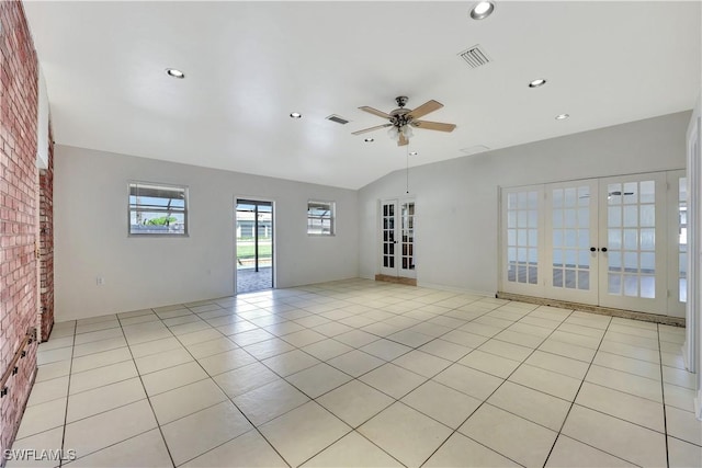 empty room with light tile patterned flooring, brick wall, ceiling fan, and french doors