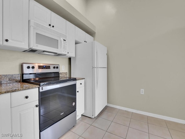 kitchen with white appliances, dark stone counters, light tile patterned floors, and white cabinets