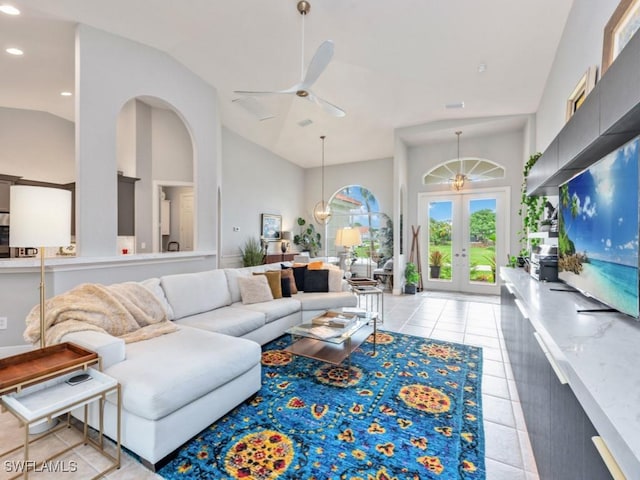 tiled living room with ceiling fan, high vaulted ceiling, and french doors