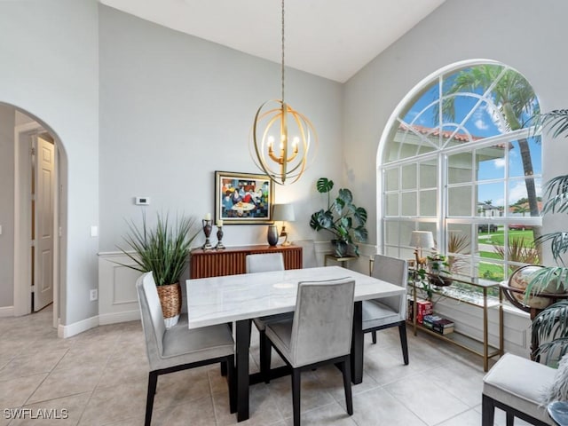 tiled dining area with a healthy amount of sunlight, vaulted ceiling, and a notable chandelier