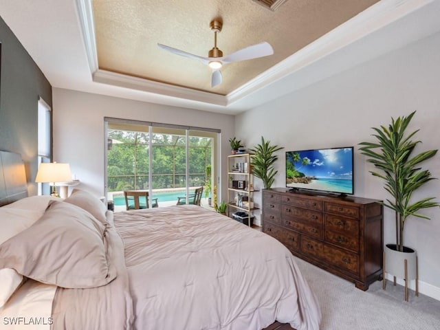 bedroom with light colored carpet, ceiling fan, a tray ceiling, crown molding, and a textured ceiling