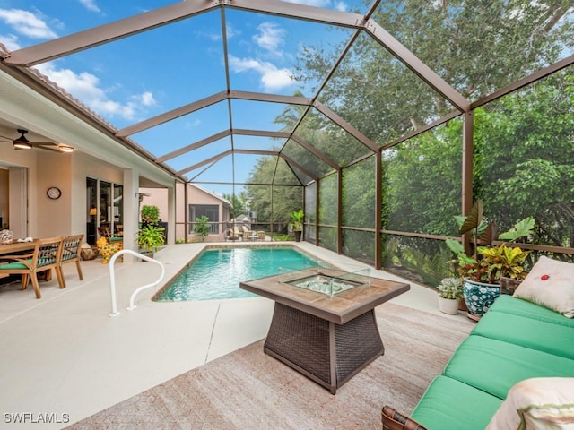 view of swimming pool featuring glass enclosure, a patio area, and an outdoor living space with a fire pit