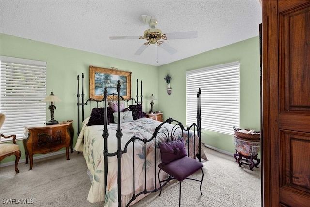 bedroom featuring a textured ceiling, light colored carpet, and ceiling fan