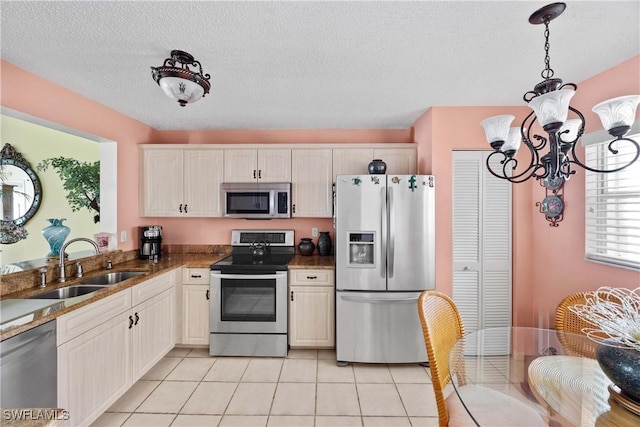 kitchen featuring pendant lighting, sink, light tile patterned floors, stainless steel appliances, and a notable chandelier